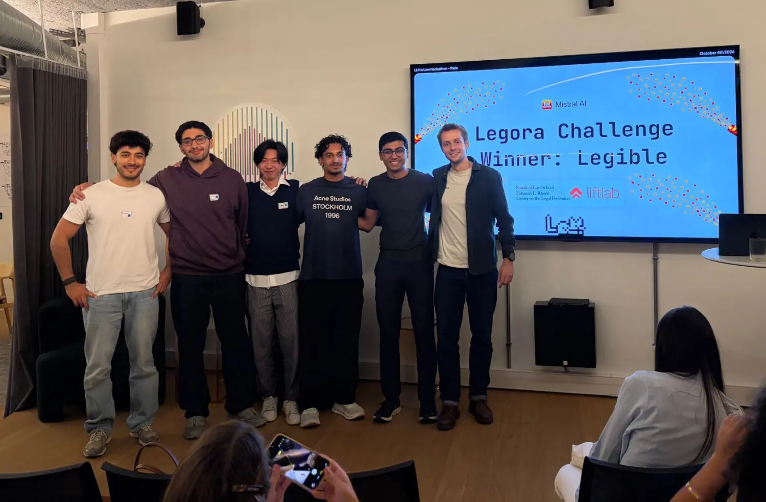 The team on stage in front of a screen reading Legora Challenge Winner: Legible